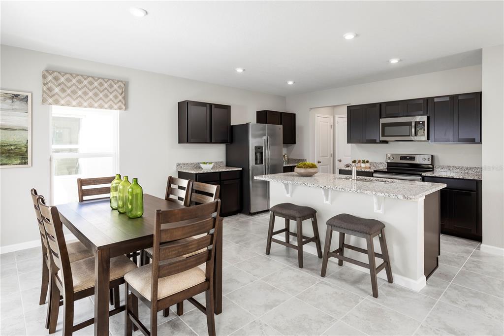 A kitchen and dining area with dark wood cabinets, granite countertops, and tile flooring — 6938 SUNDIAL DRIVE, LAKELAND, FL