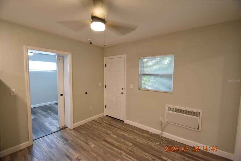 A bedroom features light-colored walls, wood-look flooring, a ceiling fan, and a window air conditioner — 419 STREMMA ROAD, LARGO, FL