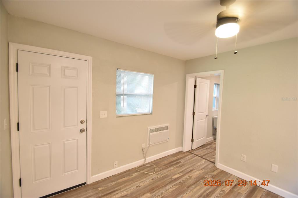 An interior room features light-colored walls, wood-look flooring, a white door, and a window — 419 STREMMA ROAD, LARGO, FL