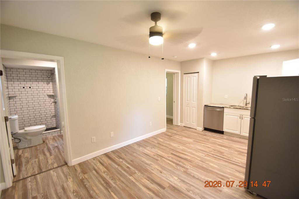 A room with wood-look flooring features an open kitchen area and an adjacent bathroom — 419 STREMMA ROAD, LARGO, FL