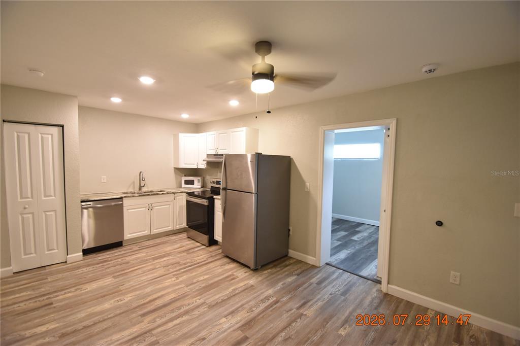 A kitchen features white cabinets, stainless steel appliances, and wood-look flooring — 419 STREMMA ROAD, LARGO, FL