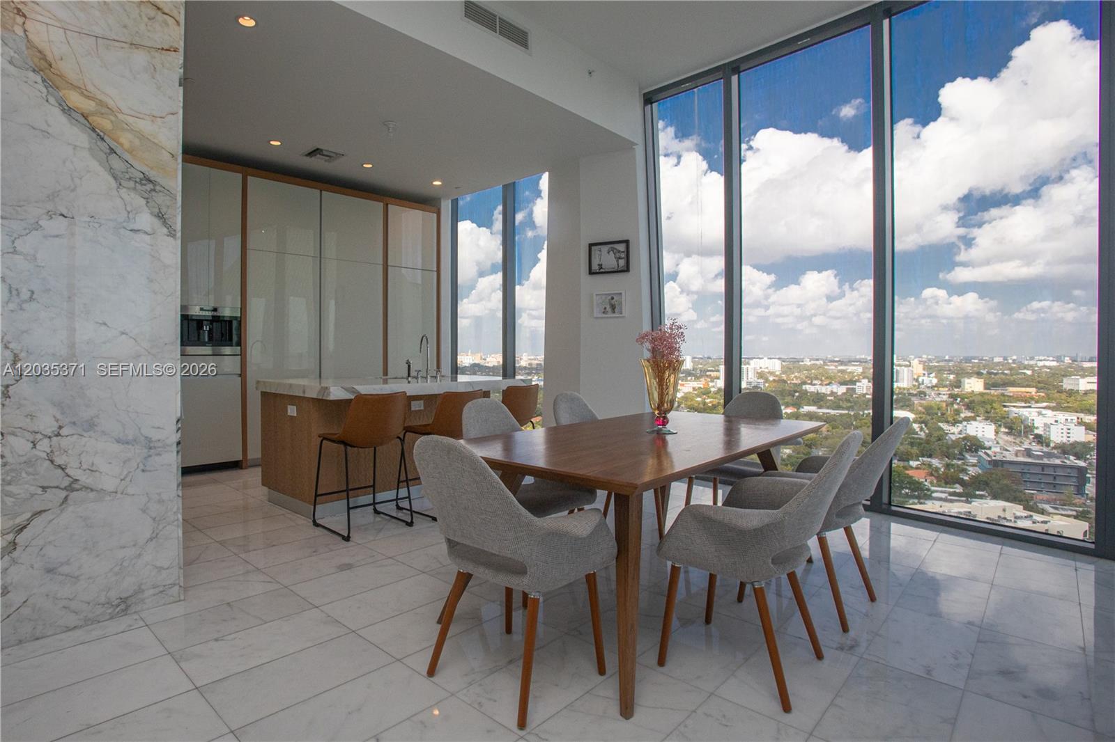 A modern dining area and kitchen with floor-to-ceiling windows overlooking a city skyline — 2821 S Bayshore Dr # 20D, Miami FL 33133, MIAMI, FL