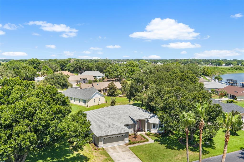An aerial view shows a single-story house with a gray roof and a concrete driveway — 220 HARTRIDGE HILLS DR, WINTER HAVEN, FL