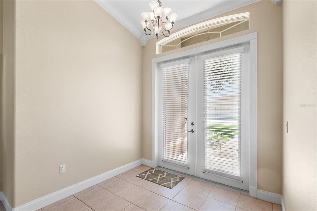 A tiled entryway features a chandelier, a large blank wall, and double glass doors — 220 HARTRIDGE HILLS DR, WINTER HAVEN, FL