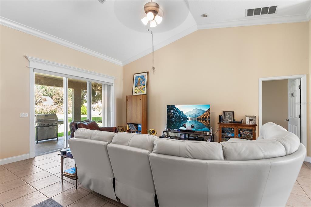 A living room features a white sectional sofa, vaulted ceilings, and sliding glass doors to a patio — 220 HARTRIDGE HILLS DR, WINTER HAVEN, FL