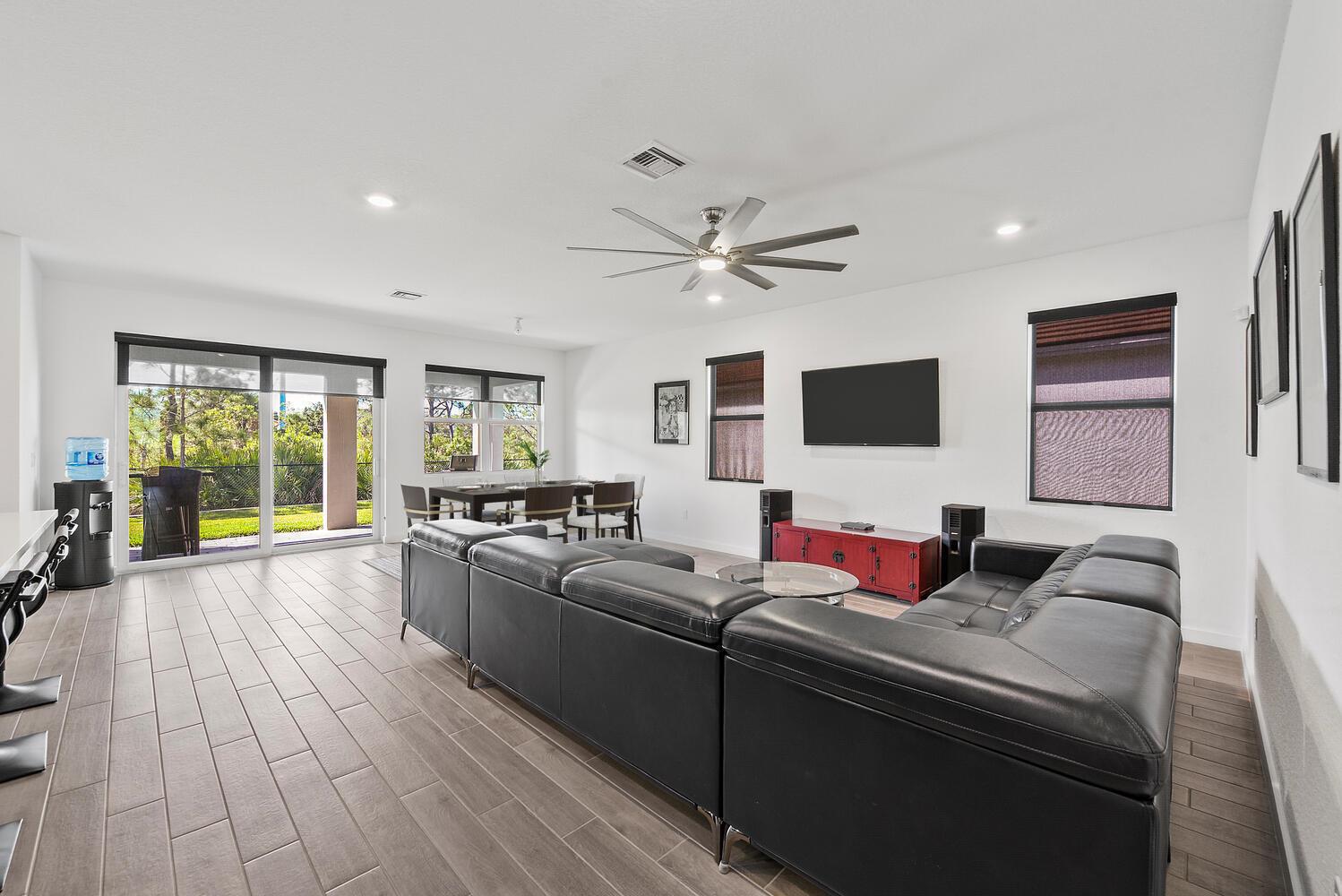 A living room with a black sectional, dining area, and sliding glass doors to a yard — 4444 NW King Court, Jensen Beach FL 34957, JENSEN BEACH, FL