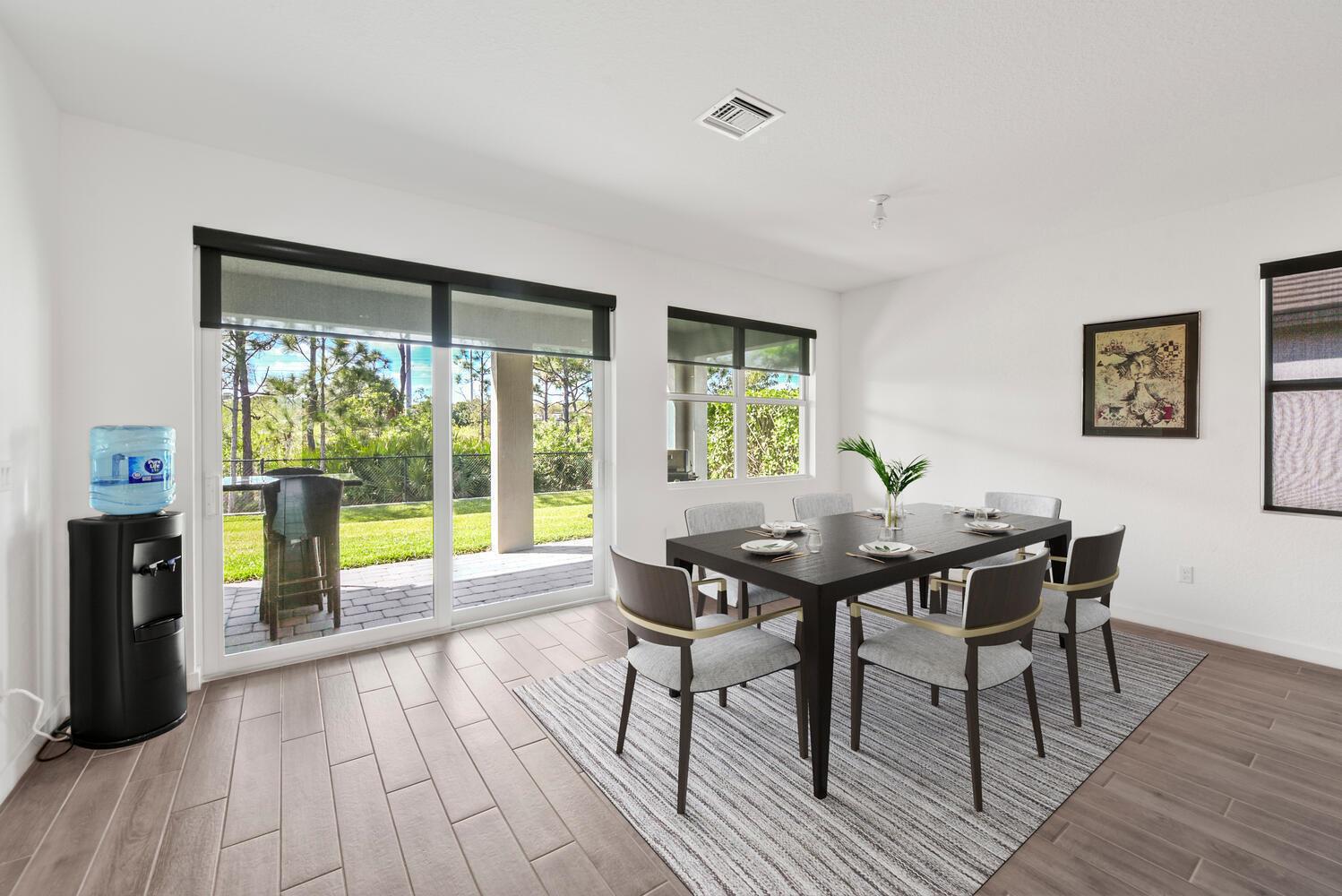 A dining room features a dark wood table, six chairs, a rug, and sliding glass doors — 4444 NW King Court, Jensen Beach FL 34957, JENSEN BEACH, FL