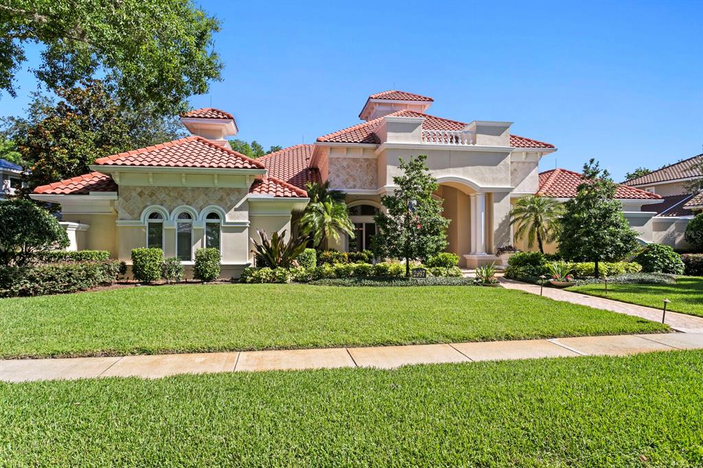 A single-story Mediterranean-style house with a red tile roof and a manicured front lawn — 2997 KENSINGTON TRACE, TARPON SPRINGS, FL