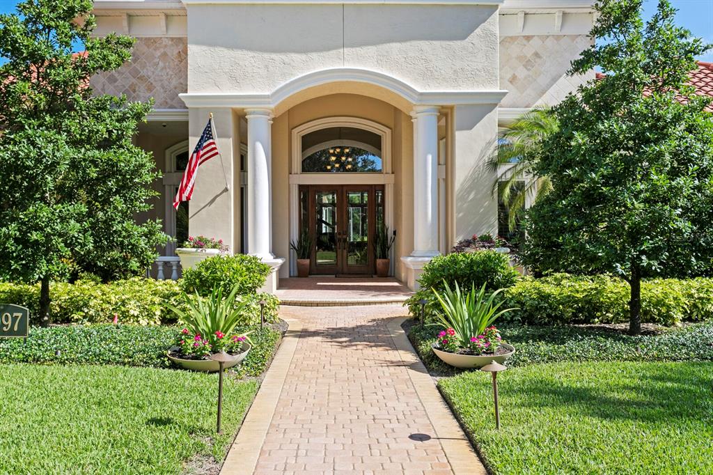 A brick walkway leads to the arched entryway of a house with white columns — 2997 KENSINGTON TRACE, TARPON SPRINGS, FL
