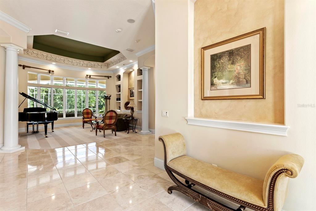 A foyer with a beige bench leads into a living room featuring a grand piano — 2997 KENSINGTON TRACE, TARPON SPRINGS, FL