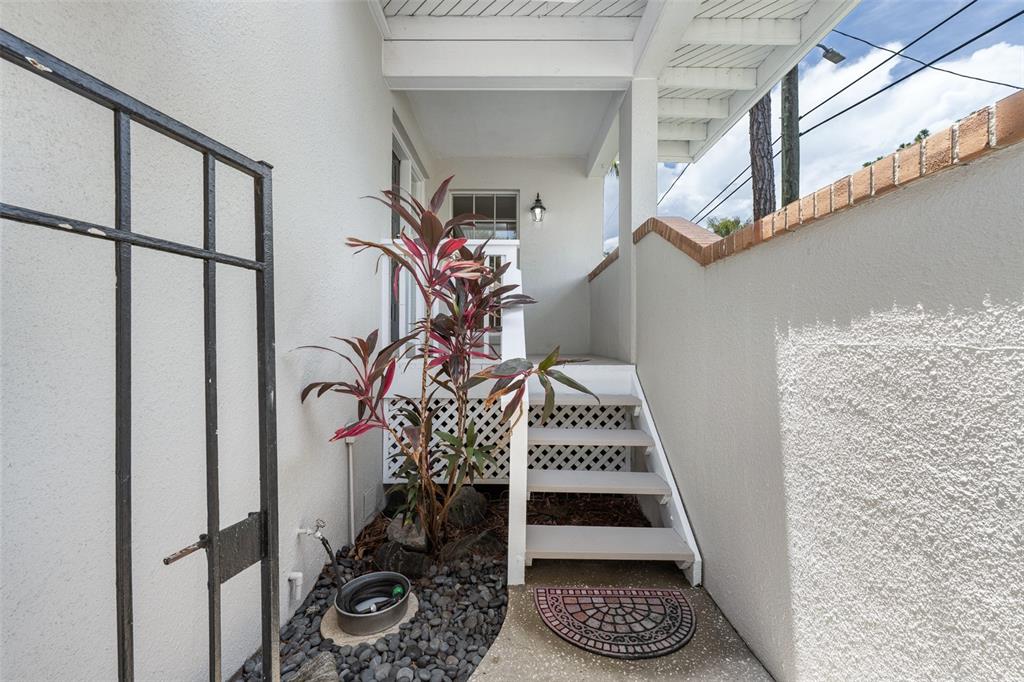 An outdoor staircase leads to a covered porch beside a white stucco wall and plant — 5116 BAYSHORE BOULEVARD, TAMPA, FL