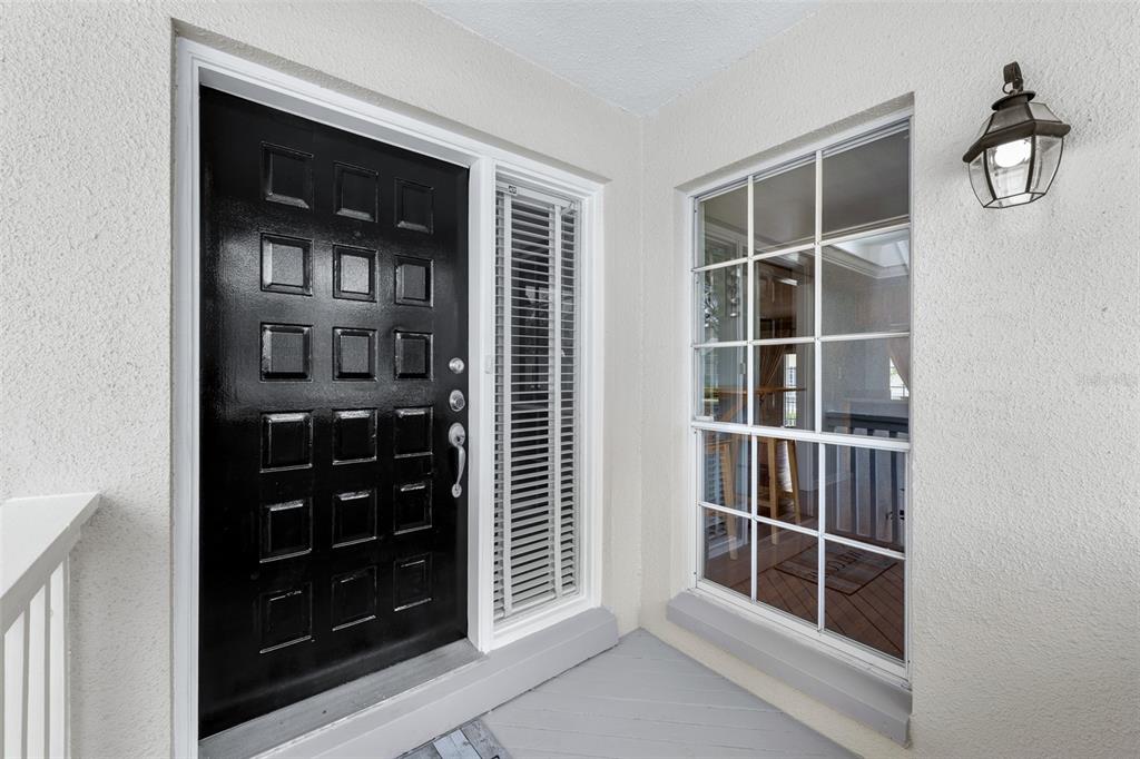 A black front door with square panels sits next to a window on a porch — 5116 BAYSHORE BOULEVARD, TAMPA, FL