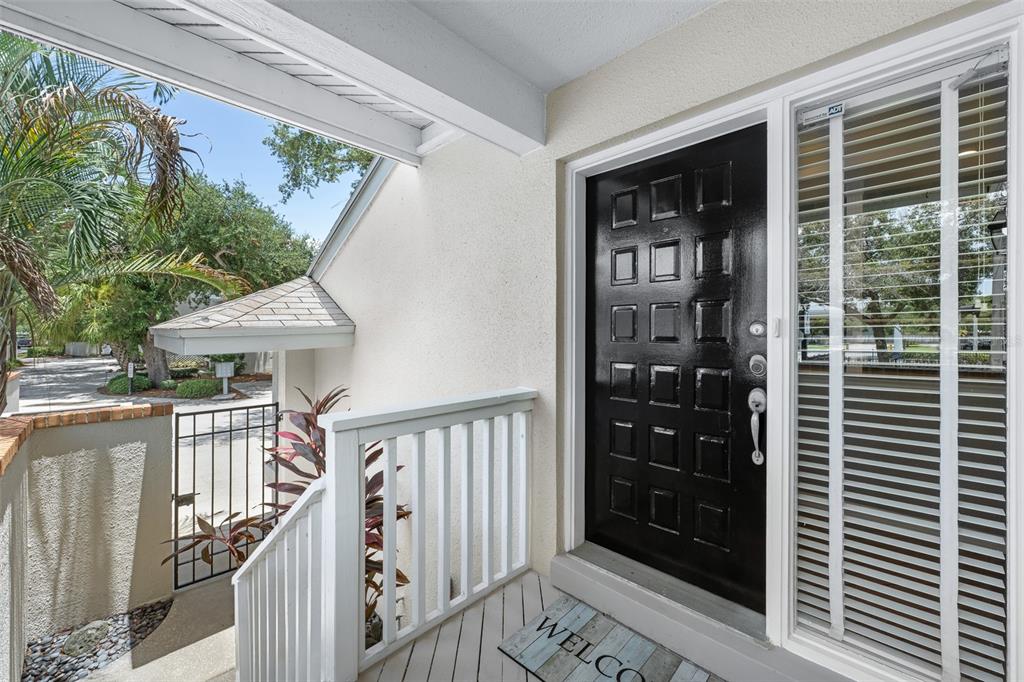 A black front door with a grid pattern sits on a porch with white railings — 5116 BAYSHORE BOULEVARD, TAMPA, FL