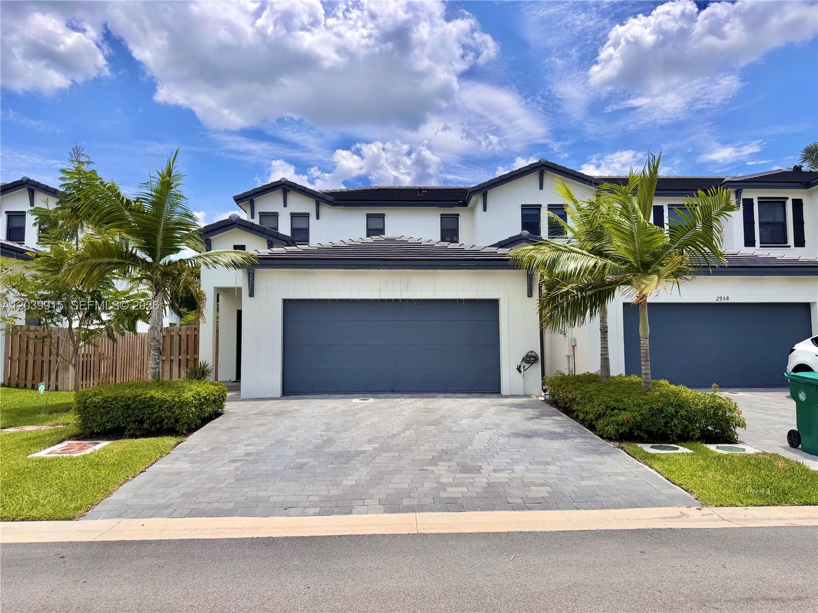 A two-story townhouse with a gray garage door, paved driveway, and two palm trees — 2950 Park Pl # 5838, Dania Beach FL 33312, DANIA BEACH, FL