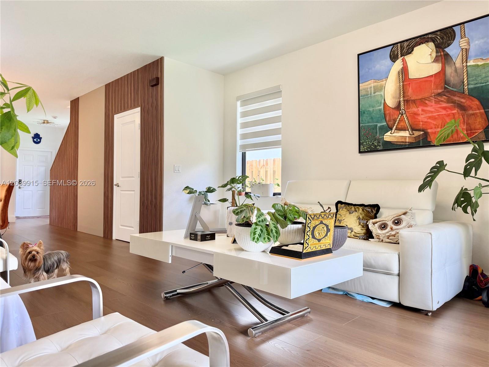 A living room features a white sofa, a modern coffee table, and wood-paneled accent walls — 2950 Park Pl # 5838, Dania Beach FL 33312, DANIA BEACH, FL