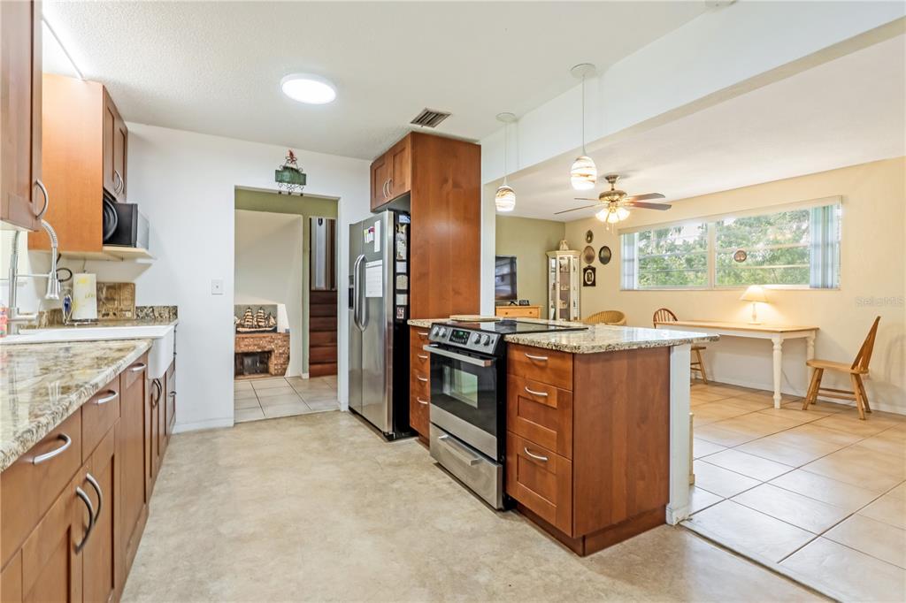 A kitchen with wood cabinets, granite countertops, stainless steel appliances, and an adjacent dining area — 24 OAK STREET, PORT ORANGE, FL