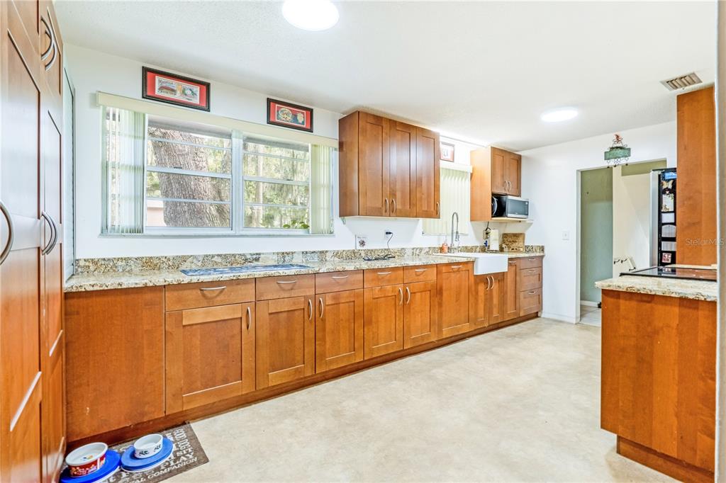 A kitchen features wood cabinets, granite countertops, a farmhouse sink, and a large window — 24 OAK STREET, PORT ORANGE, FL