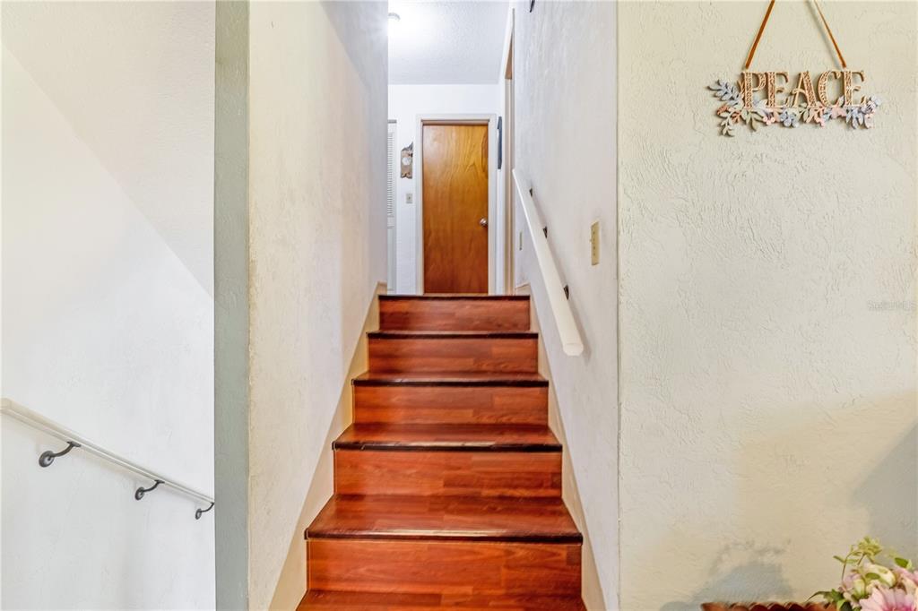 A staircase with wood treads leads up to a landing with a wooden door — 24 OAK STREET, PORT ORANGE, FL