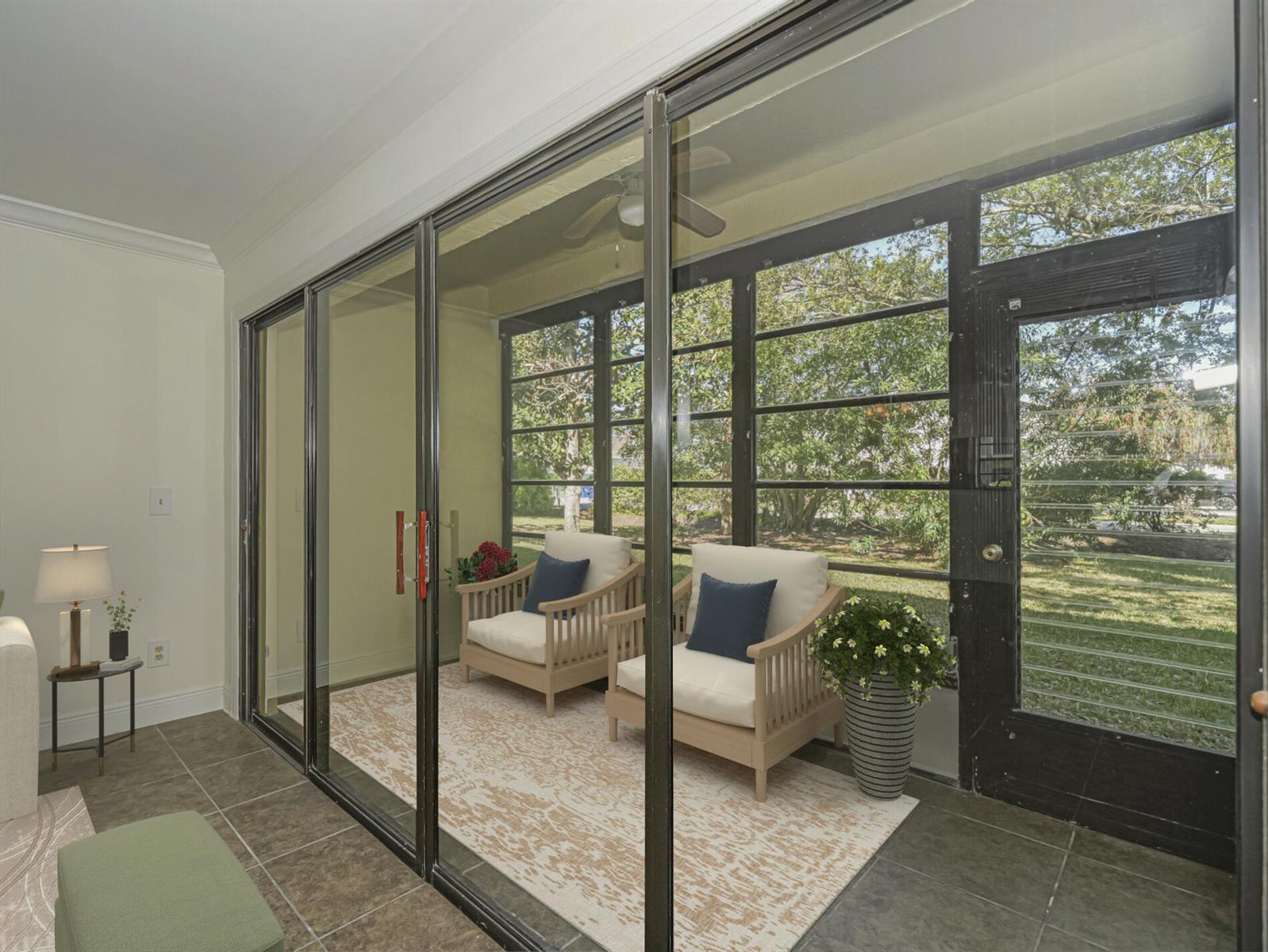 A sunroom features tile flooring, sliding glass doors, and two chairs on a patterned rug — 400 18th Street # G2, Vero Beach FL 32960, VERO BEACH, FL