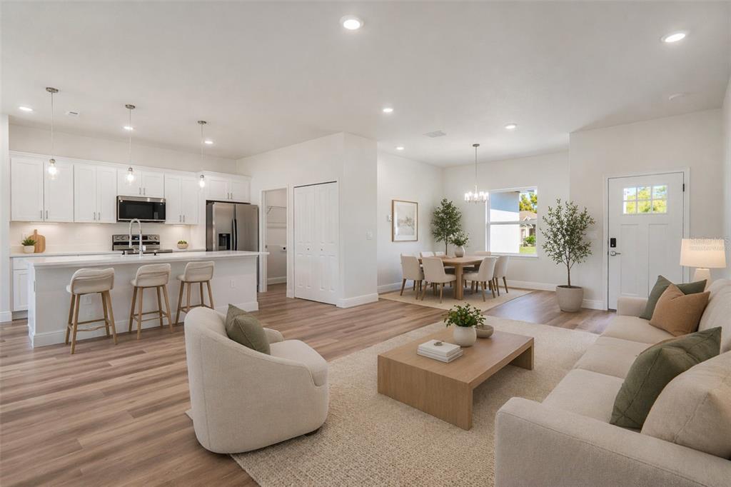 An open-concept living room, dining area, and kitchen with white cabinets and wood-look flooring — 3908 SW 171ST LANE, OCALA, FL