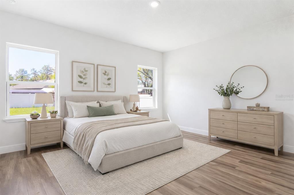 A bright bedroom features a neutral color palette, wood-look flooring, and a large dresser — 3908 SW 171ST LANE, OCALA, FL