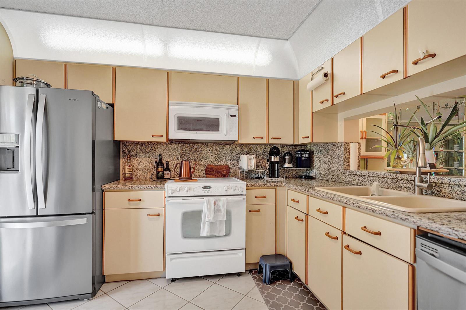 A kitchen features light-colored cabinets, granite countertops, stainless steel appliances, and a white stove — 5201 W Club Circle # 103, Boca Raton FL 33431, BOCA RATON, FL