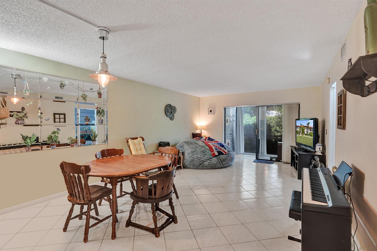 A dining area and living space with tile floors, a beanbag chair, and sliding doors — 5201 W Club Circle # 103, Boca Raton FL 33431, BOCA RATON, FL