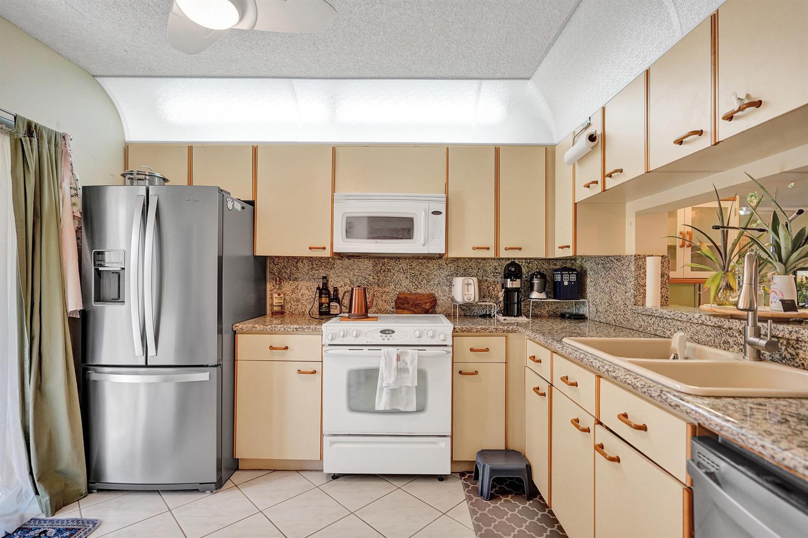 A kitchen features light-colored cabinets, granite countertops, stainless steel appliances, and a white stove — 5201 W Club Circle # 103, Boca Raton FL 33431, BOCA RATON, FL