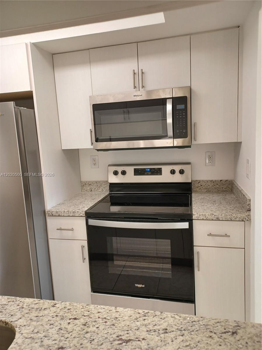 A kitchen features white cabinets, granite countertops, and stainless steel appliances — 8275 SW 152nd Ave # 416, Miami FL 33193, MIAMI, FL