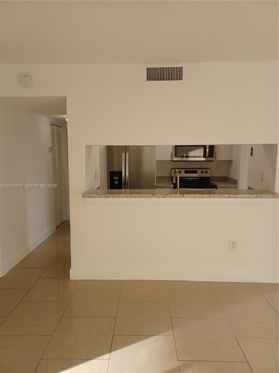A kitchen with stainless steel appliances is visible through a pass-through window above a counter — 8275 SW 152nd Ave # 416, Miami FL 33193, MIAMI, FL