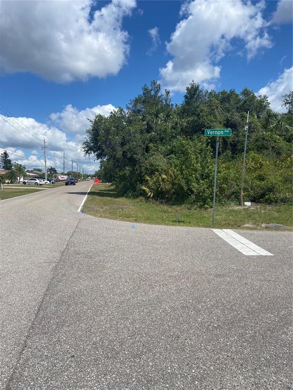 A street corner features a Vernon Ave sign next to a wooded, undeveloped lot — 1190 VERNON AVE, PORT CHARLOTTE, FL