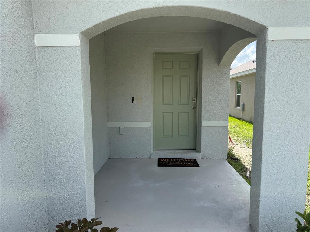 A covered front porch leads to a light green door with a welcome mat — 8594 SW 46TH AVENUE, OCALA, FL