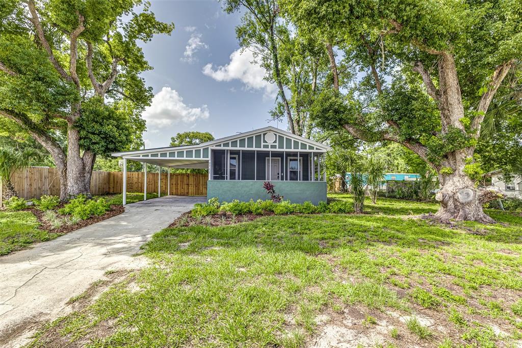 A single-story house with a screened front porch, attached carport, and large trees in front — 2711 CRUTCHFIELD ROAD, LAKELAND, FL
