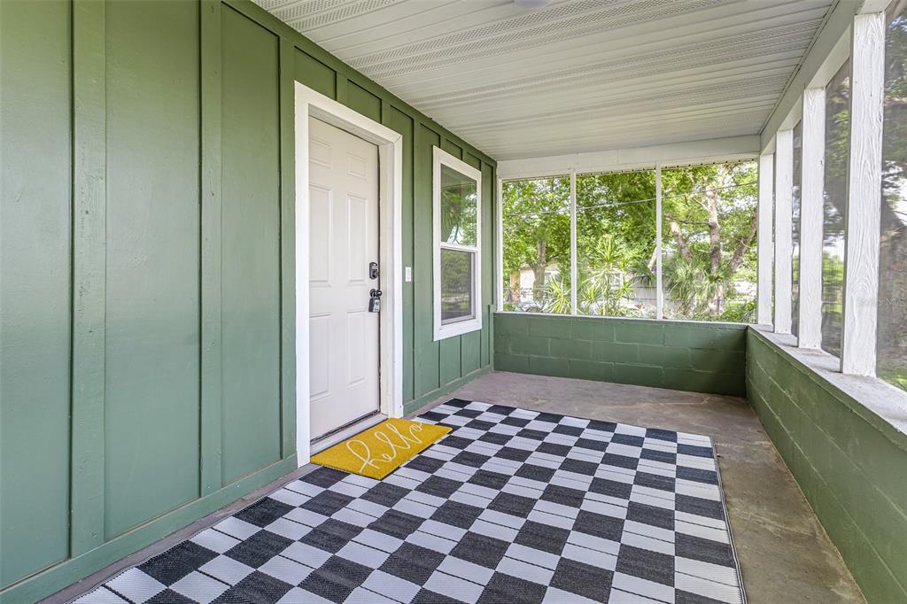 A screened-in porch features green board-and-batten walls, a concrete floor, and a checkered rug — 2711 CRUTCHFIELD ROAD, LAKELAND, FL