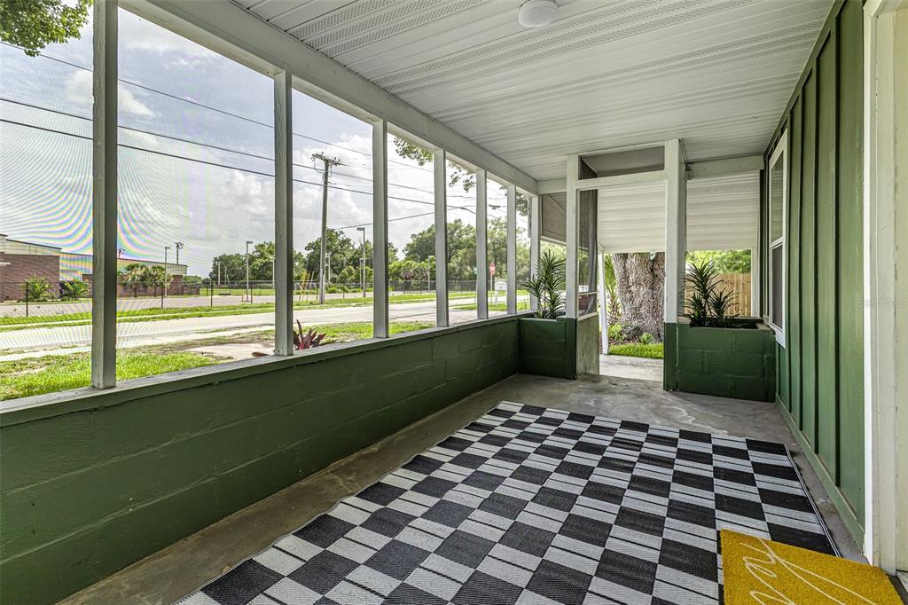A screened-in porch features green block walls, a checkered rug, and views of the street — 2711 CRUTCHFIELD ROAD, LAKELAND, FL