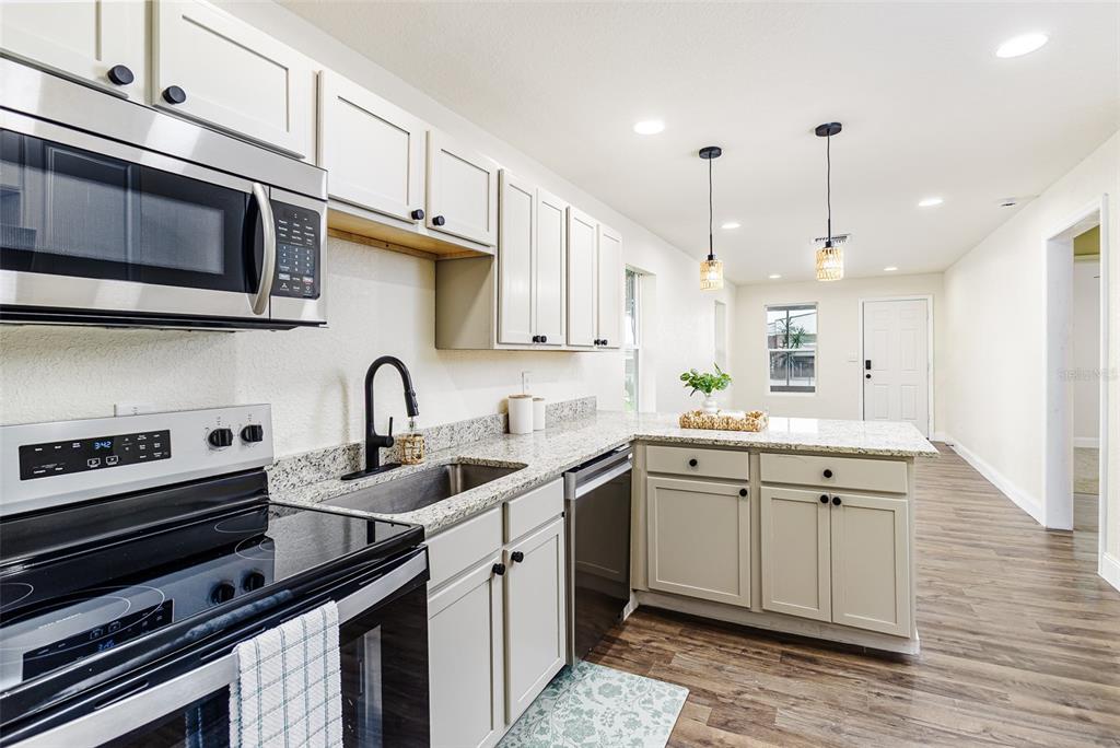 A kitchen features light-colored cabinets, granite countertops, stainless steel appliances, and wood-look flooring — 2711 CRUTCHFIELD ROAD, LAKELAND, FL