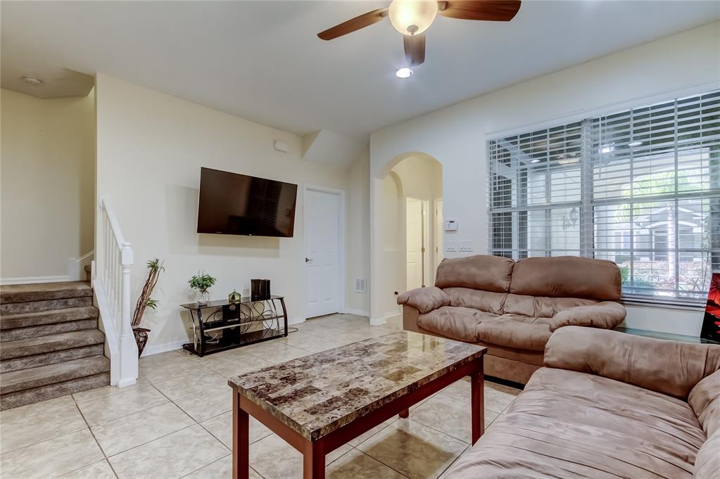A living room features tile flooring, a mounted television, brown sofas, and a ceiling fan — 12660 SILVERDALE STREET, TAMPA, FL