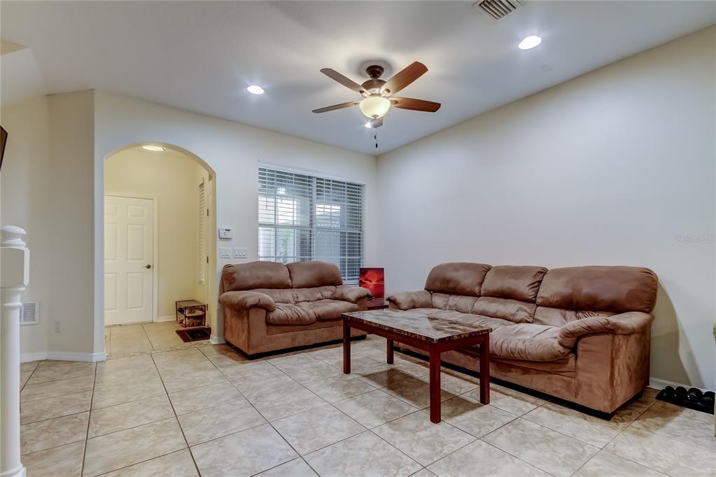 A living room features beige tile flooring, two brown sofas, a coffee table, and a fan — 12660 SILVERDALE STREET, TAMPA, FL