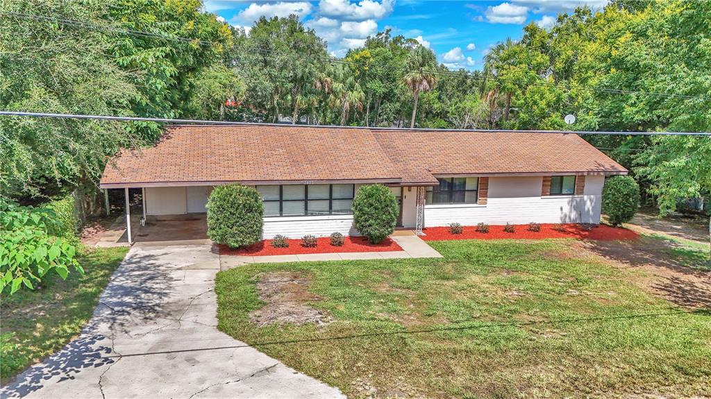A single-story house with a brown shingled roof, white brick exterior, and a concrete driveway — 2433 NE 2ND STREET, OCALA, FL