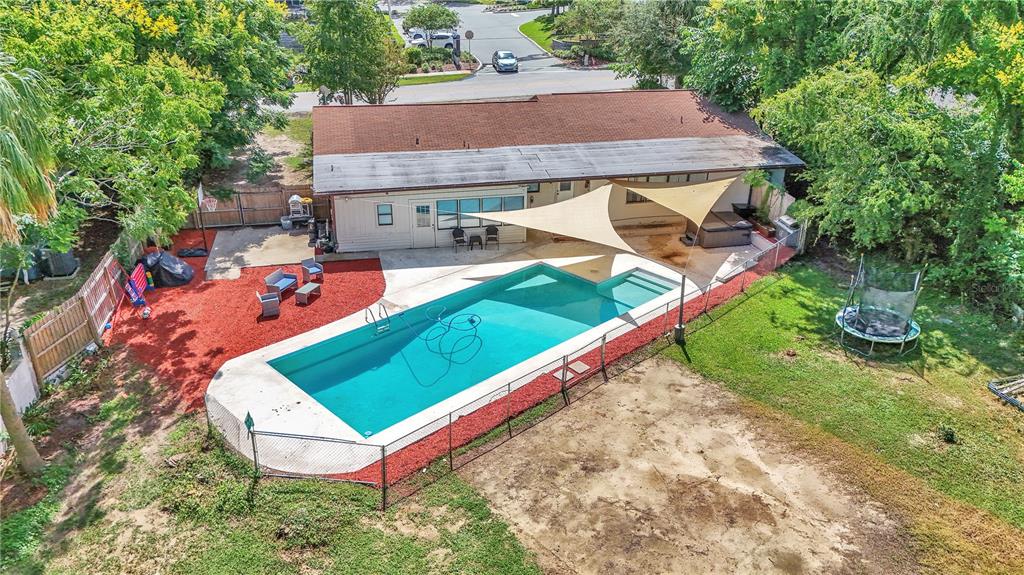 An aerial view of a backyard featuring a rectangular swimming pool, patio, and shade sail — 2433 NE 2ND STREET, OCALA, FL