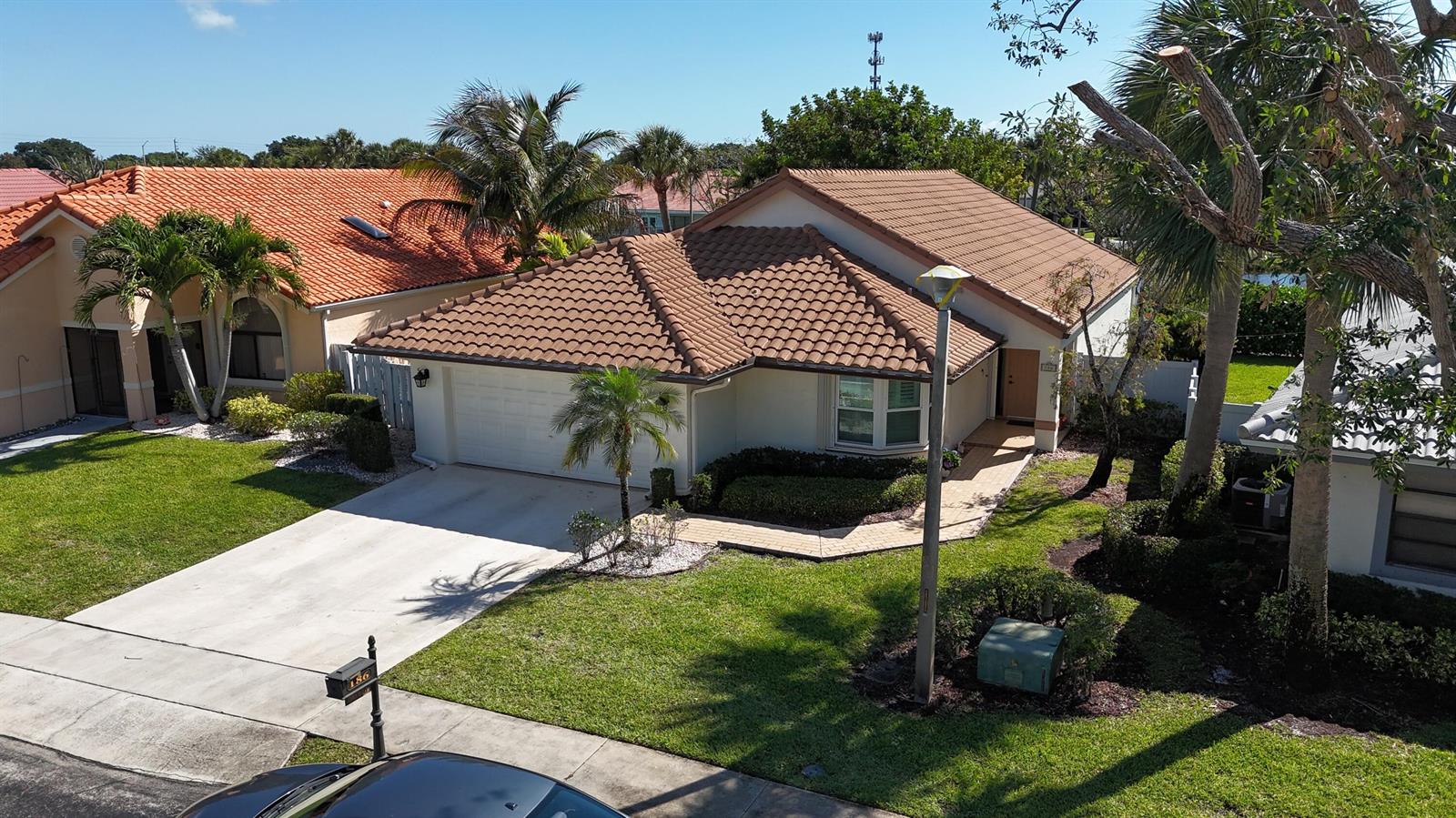 An exterior view of a single-story house with a tiled roof and a concrete driveway — 186 Citrus Trail Circle, Boynton Beach FL 33436, BOYNTON BEACH, FL