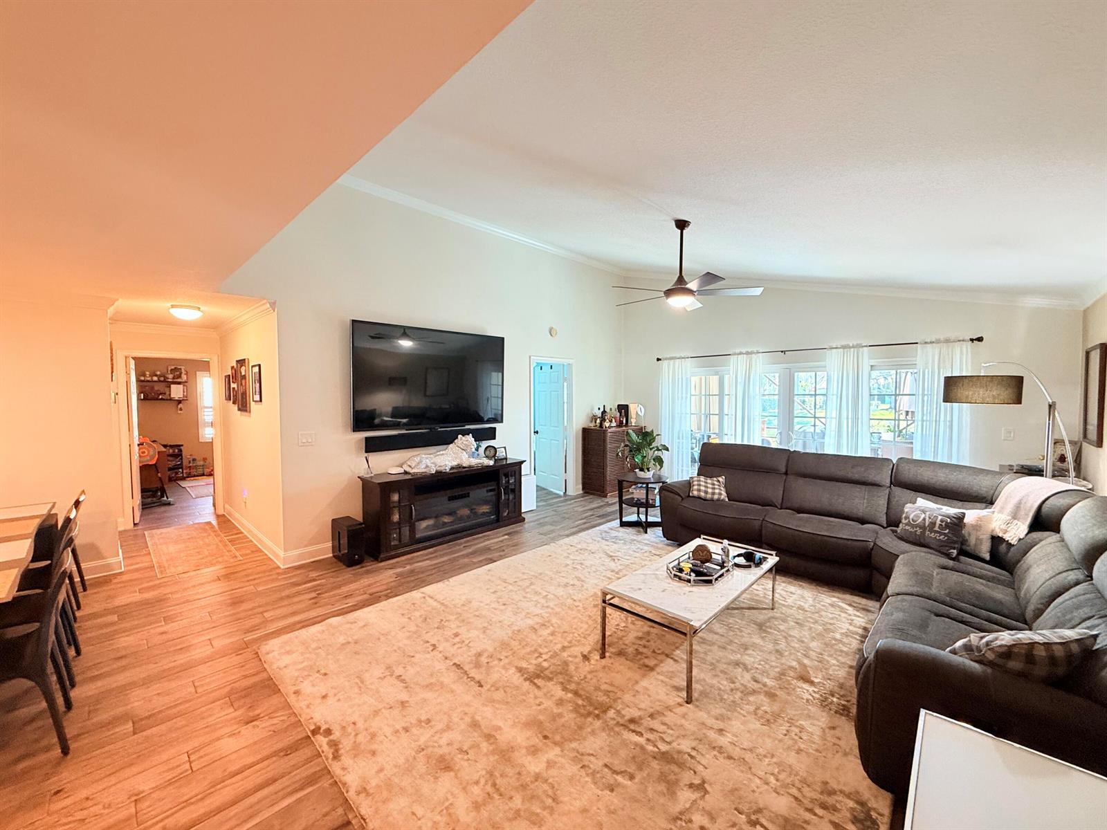 A spacious living room features wood-look flooring, a large sectional sofa, and a wall-mounted television — 186 Citrus Trail Circle, Boynton Beach FL 33436, BOYNTON BEACH, FL