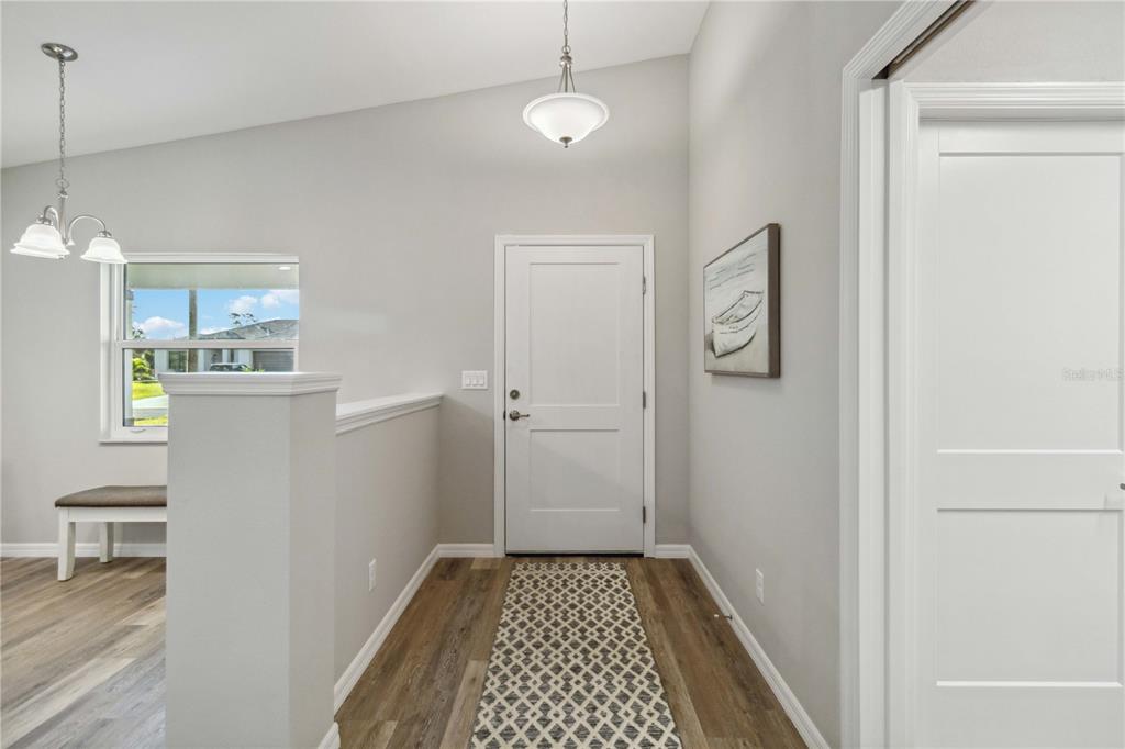 An entryway features a white door, light gray walls, wood-look flooring, and a pendant light — 6316 DEER RUN RD, NORTH PORT, FL