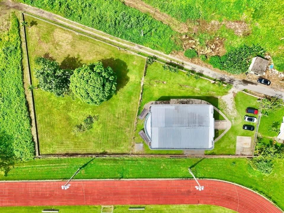 An aerial view shows a house with a metal roof on a fenced grassy lot — Carr. 760 KM 0.4 BO. EMAJAGUAS, MAUNABO, PR