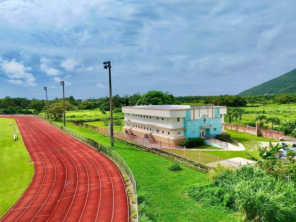 An aerial view of a running track next to a two-story building with a cross — Carr. 760 KM 0.4 BO. EMAJAGUAS, MAUNABO, PR