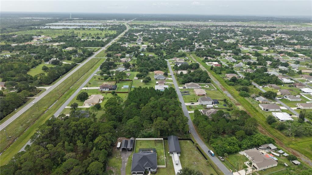 An aerial view shows a residential neighborhood with houses, wooded areas, and a long road — 2917 HESTER AVENUE SE, PALM BAY, FL