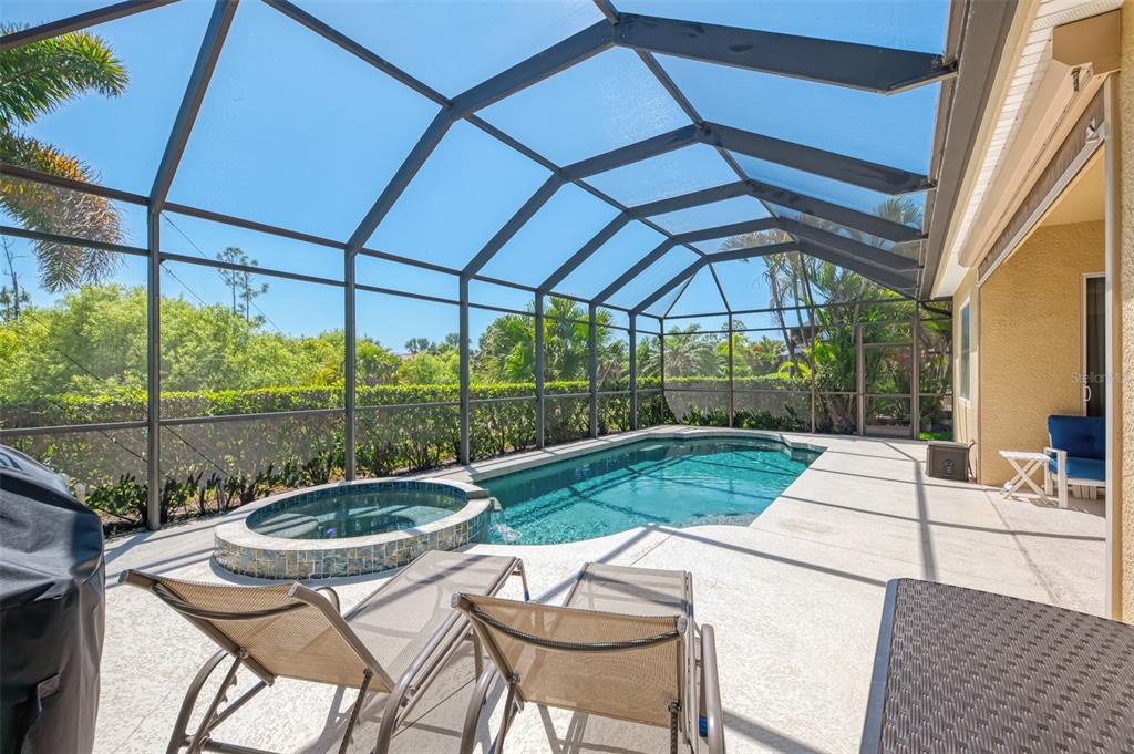 A screened-in patio features a swimming pool, a raised spa, and two lounge chairs — 13217 SCRUB JAY COURT, PORT CHARLOTTE, FL