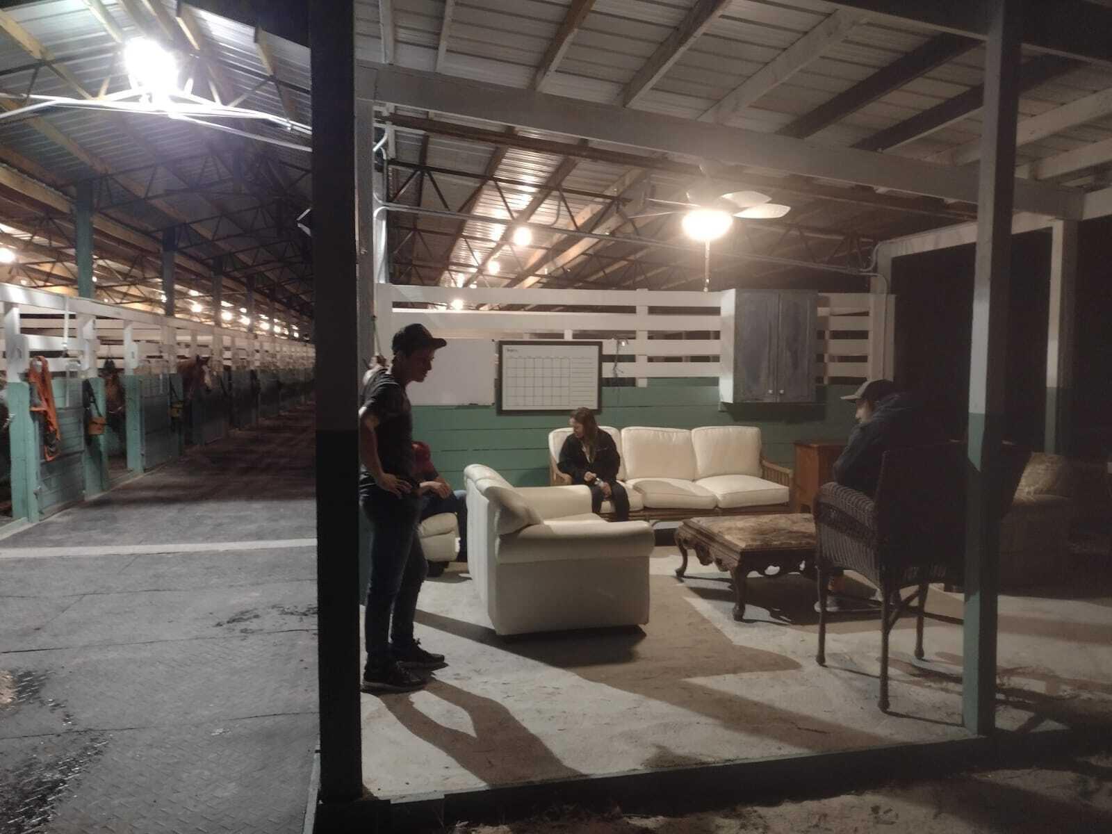 A lounge area with white sofas and a coffee table inside a horse stable — 1100 D Road, FL 33470, FL