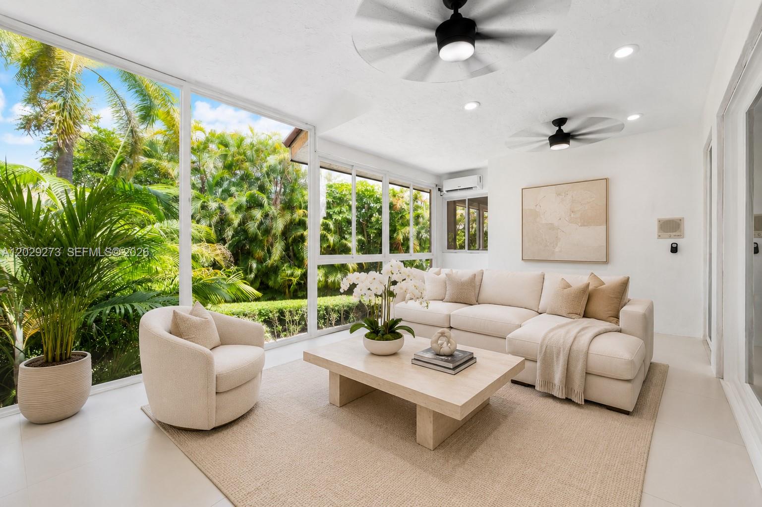A sunroom features a white sectional sofa, a swivel chair, and large windows overlooking palm trees — 2000 S Bayshore Dr # 58, Miami FL 33133, MIAMI, FL