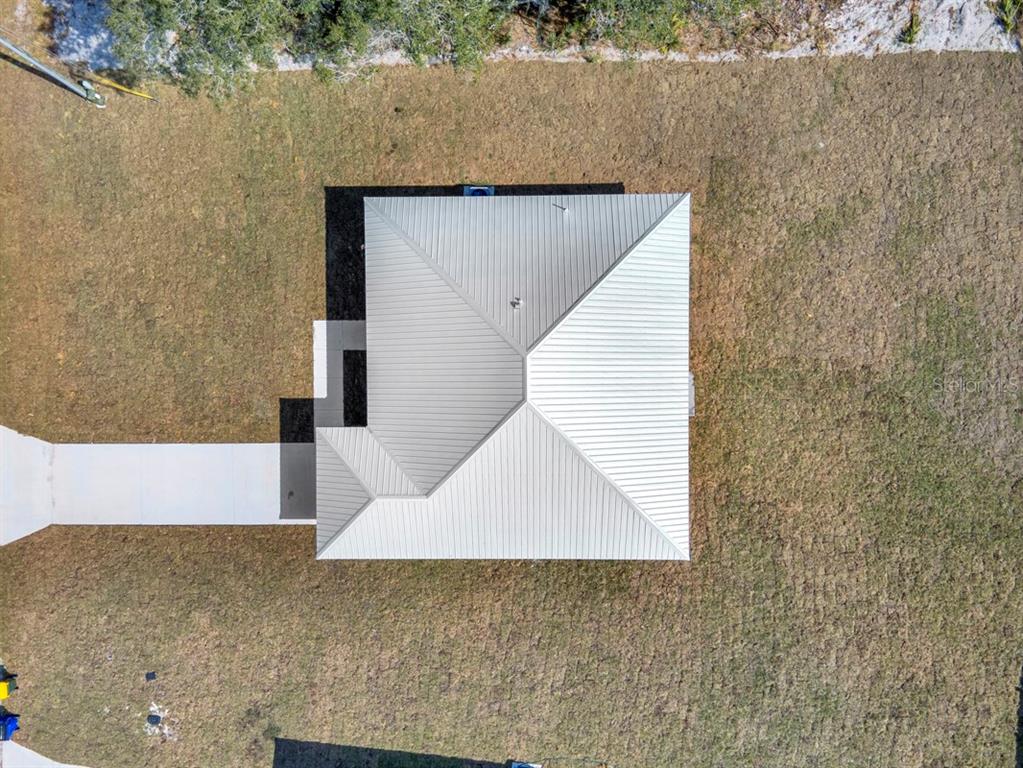 An aerial view shows a house with a metal roof and an attached concrete walkway — 4368 MERCEDES STREET, SEBRING, FL